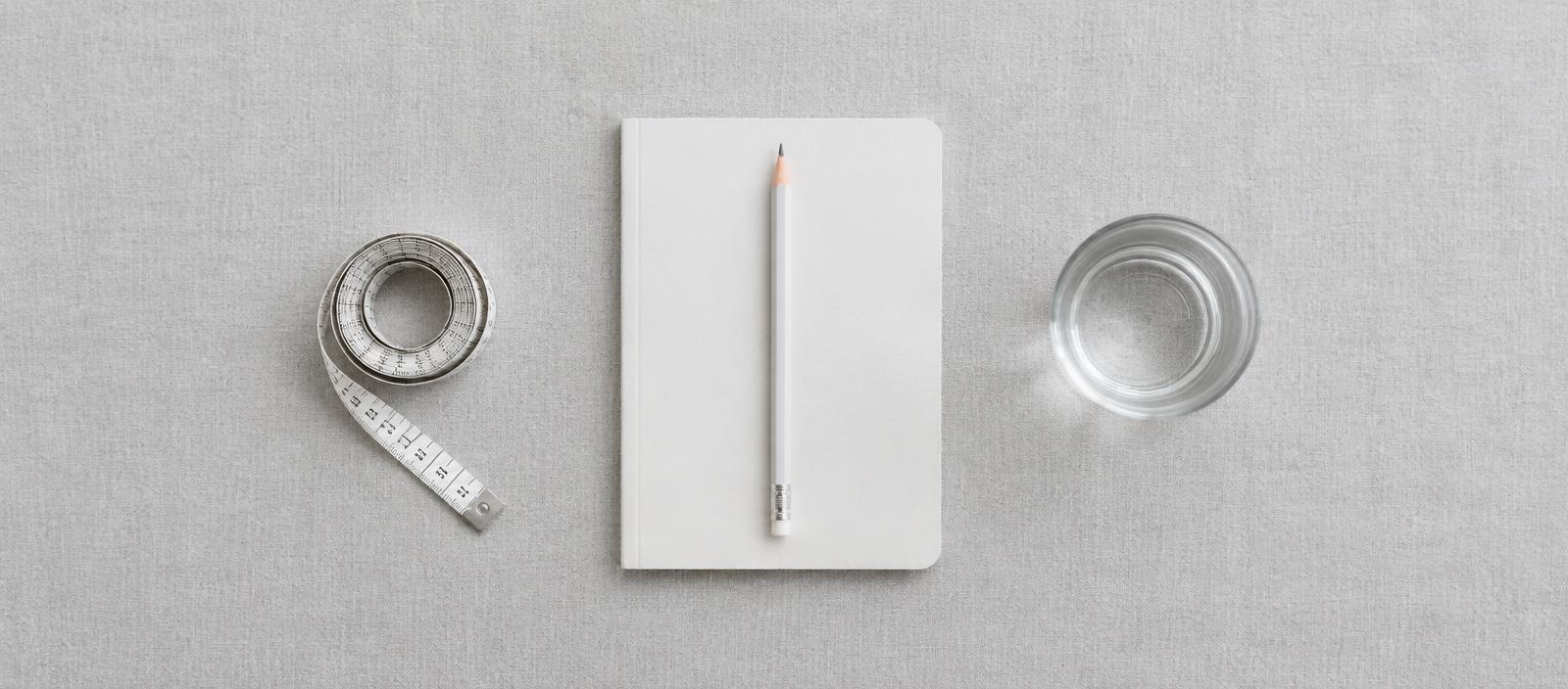 Notebook, measuring tape and glass of water